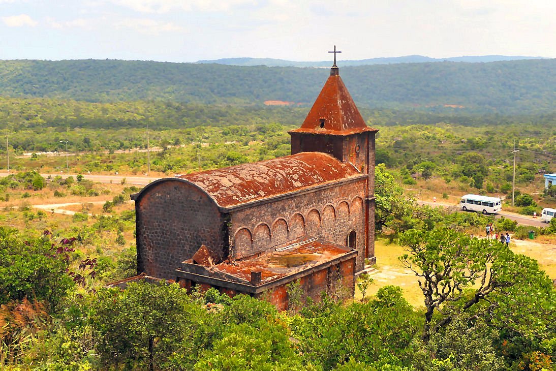 Historic red brick Old Catholic Church ruins surrounded by lush green trees in Preah Monivong Bokor National Park, Kampot Cambodia